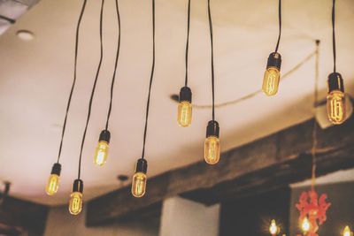 Low angle view of lights hanging against ceiling