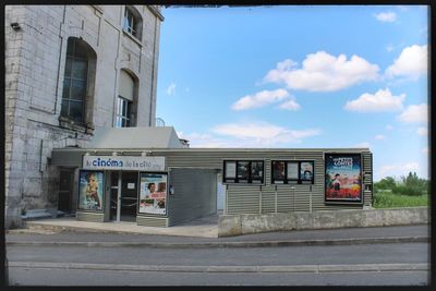 Information sign on street by building against sky