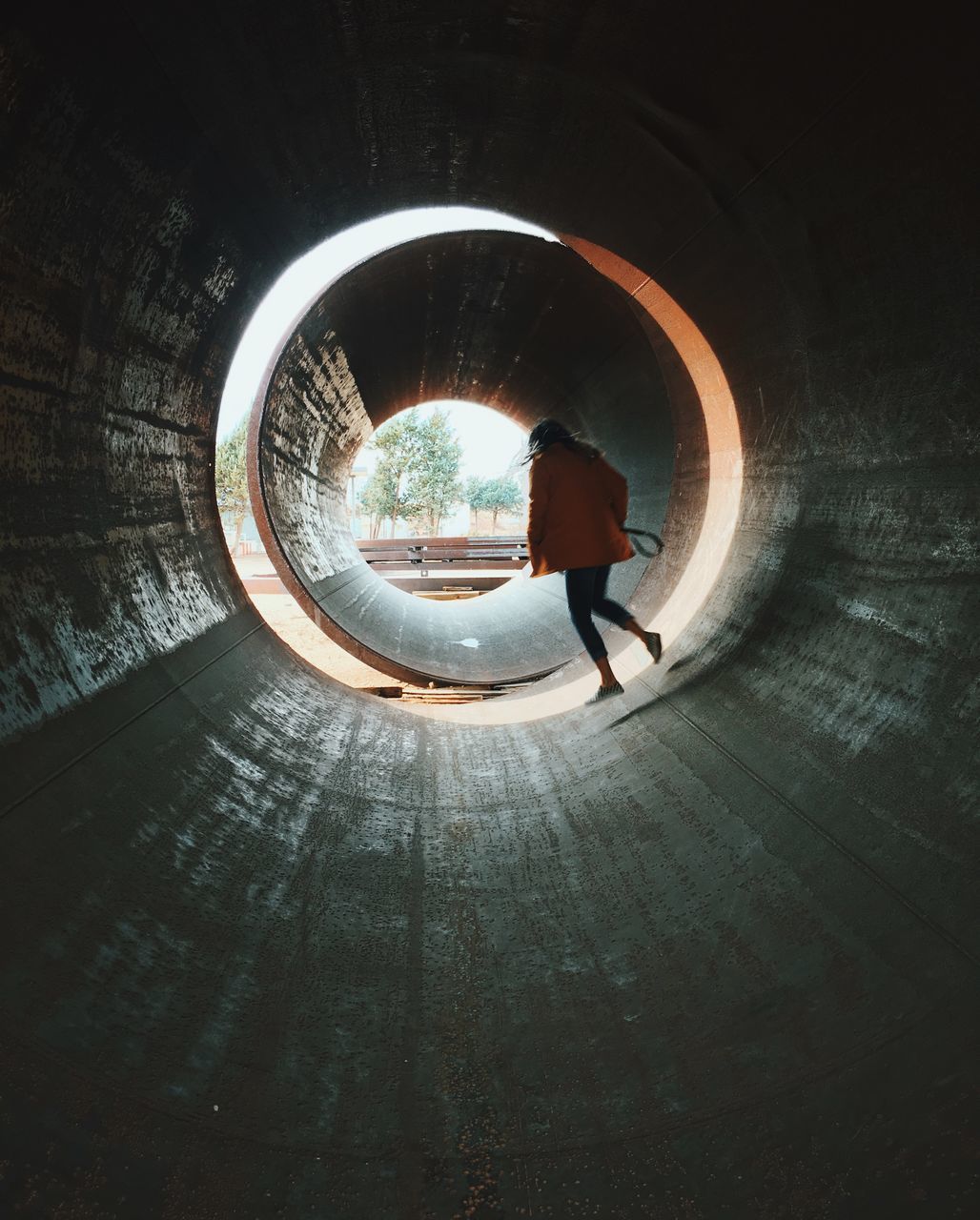 REAR VIEW OF WOMAN STANDING AT ILLUMINATED TUNNEL