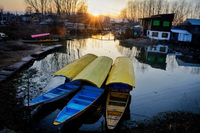 Boats moored on lake by buildings during winter