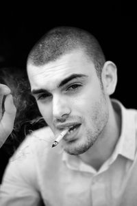 Portrait of man smoking cigarette against black background