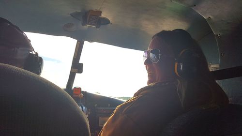 Reflection of man in car mirror against sky