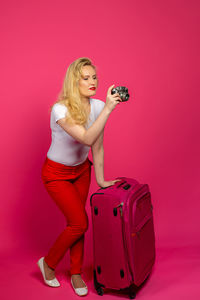Woman photographing with red hair against pink background