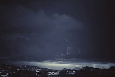 Low angle view of illuminated cityscape against cloudy sky