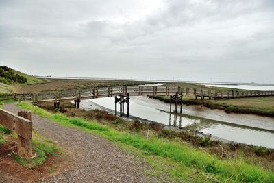 Footbridge over sea against sky