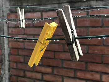 Close-up of clothespins hanging on clothesline against wall