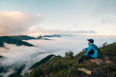 Rear view of woman standing on mountain against sky