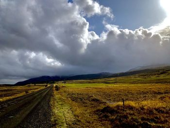 Scenic view of road amidst field against sky