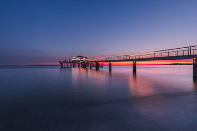 Bridge over sea against clear sky during sunset