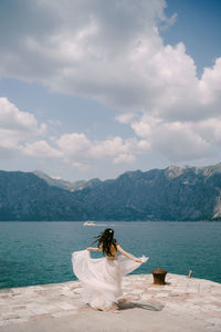 Rear view of man sitting on mountain against sky