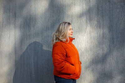 Young woman standing against orange wall