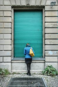 Full length of man standing against shutter