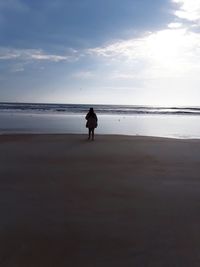 Silhouette woman standing on beach against sky