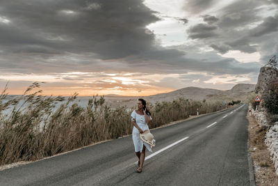 Full length portrait of man on road against sky during sunset