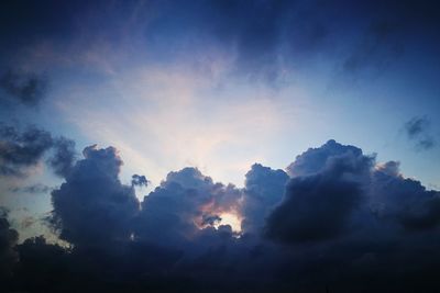 Low angle view of sunlight streaming through clouds