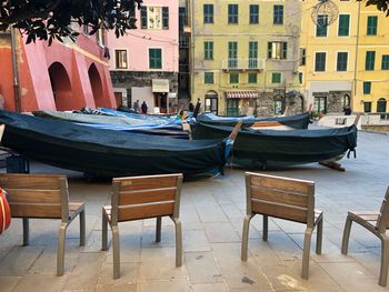 Empty chairs and tables at sidewalk cafe by buildings in city