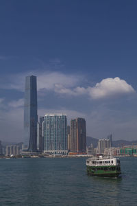 Sea by modern buildings against sky in city