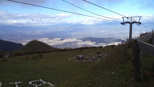 Low angle view of overhead cable cars over mountain against cloudy sky