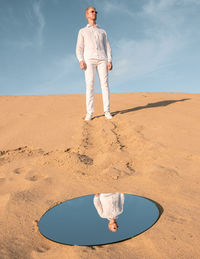 Rear view of man standing on sand at desert