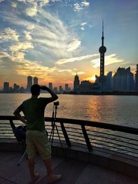 Rear view of man looking at oriental pearl tower during sunset in city