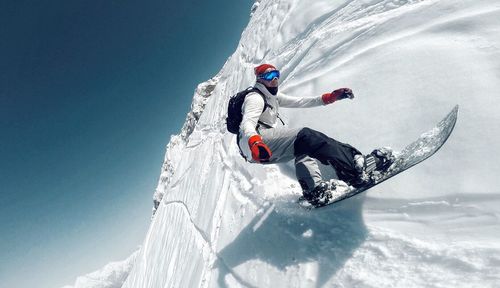 Tilt image of man snowboarding against clear sky