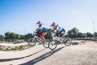 Side view of people riding bicycled on sunny day