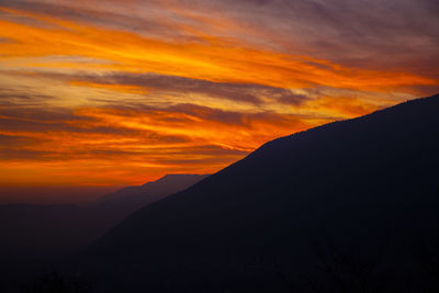 Scenic view of silhouette mountains against orange sky