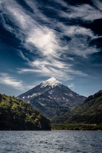 Scenic view of lake by snowcapped mountains against sky