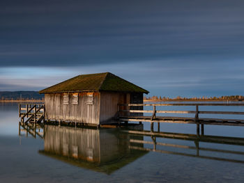 House on pier by lake against sky