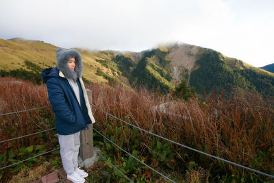 Woman standing by railing against plants during winter