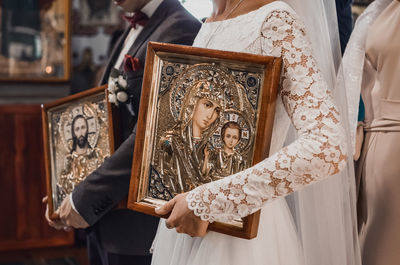 Midsection of bride holding wedding dress