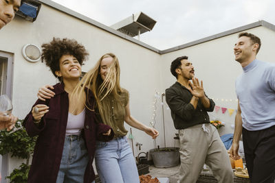 Female friends standing against building