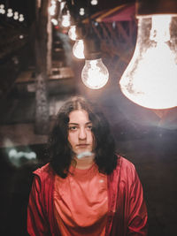 Portrait of woman standing in illuminated restaurant