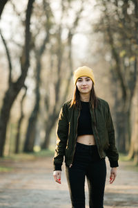 Portrait of young woman standing against tree