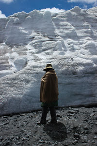Rear view of person walking by snow covered mountain