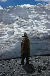 Rear view of man walking on snow covered mountain