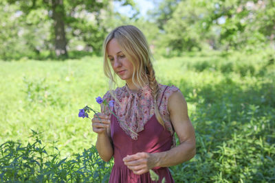 Beautiful woman standing on grass against trees