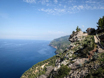 Scenic view of mountain by sea against blue sky