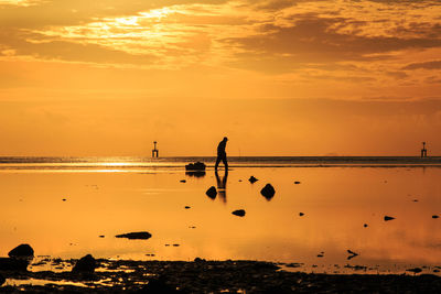 Silhouette people on beach against sky during sunset