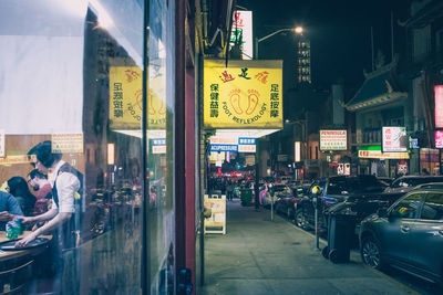 People on illuminated street in city at night