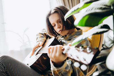 Teenage girl learning to play guitar