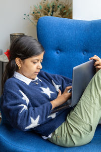 Cute girl using laptop while sitting on sofa