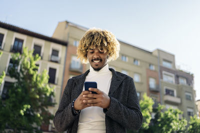 Full length of man using mobile phone against buildings