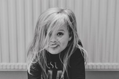 Portrait of smiling girl sticking out tongue against wall