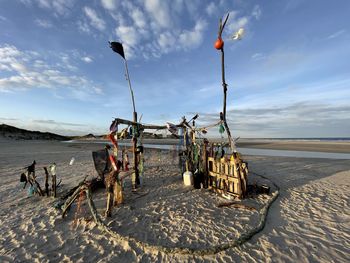 Deck chairs on beach against sky