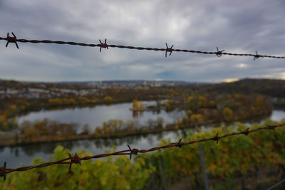 Close-up of barbed wire fence against sky