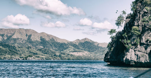 Scenic view of sea by mountains against sky