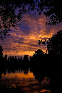 Silhouette trees by lake against sky during sunset