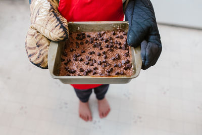 Low section of person holding baked chocolate brownie
