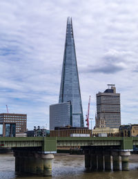 Low angle view of bridge over river against cloudy sky